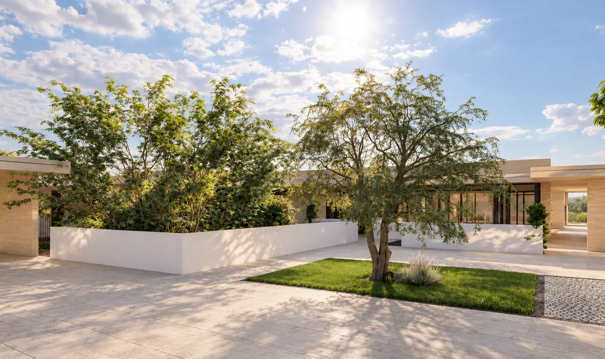 Eine Terrasse auf dem Dach: über dem hellen Steinbelag steht ein großer Baum in einer Rasenfläche, dahinter ziehen sich weiße Brüstungsmauern mit dichtem Bewuchs; rechts die verglaste Front der Wohnung, darüber offener Himmel.