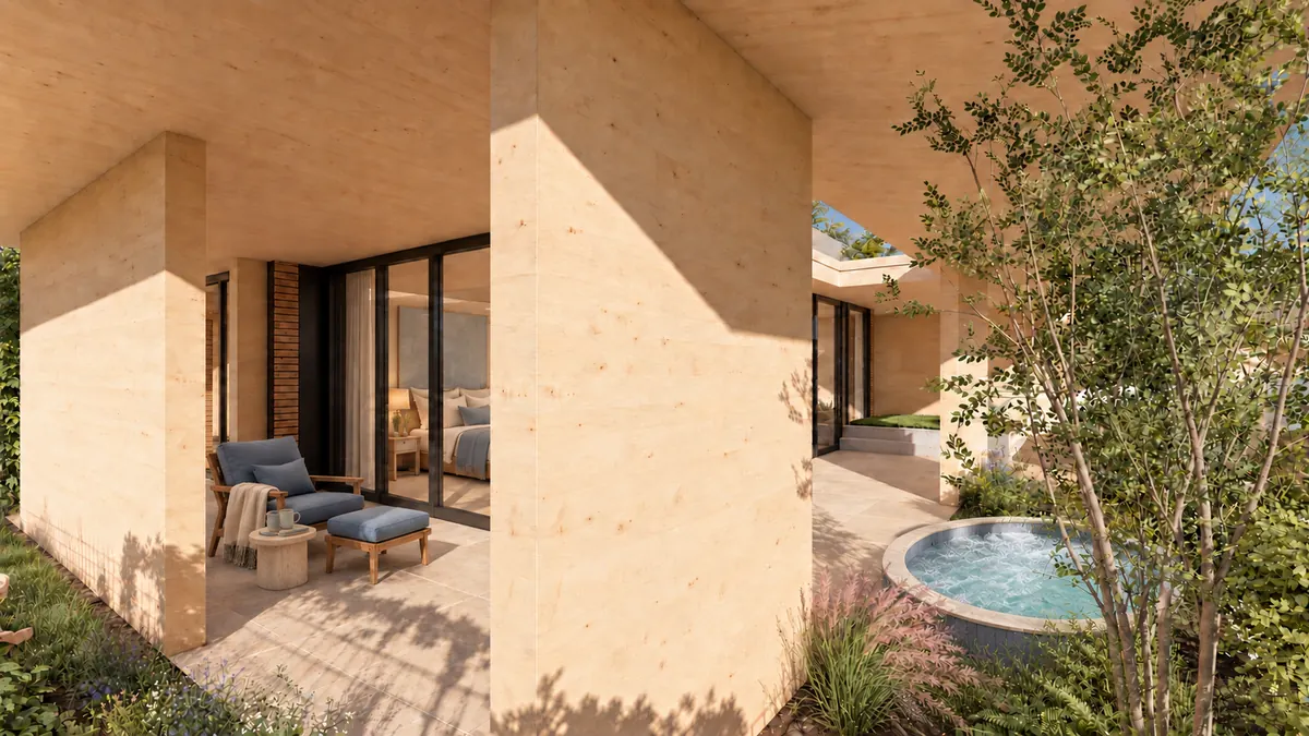 Der Blick von außen zwischen zwei Wandscheiben hindurch: links eine überdeckte Terrasse mit Sessel und Hocker vor der Schiebetür zum Schlafraum, rechts ein junger Baum und ein runder Pool im Boden, davor eine bepflanzte Fläche.