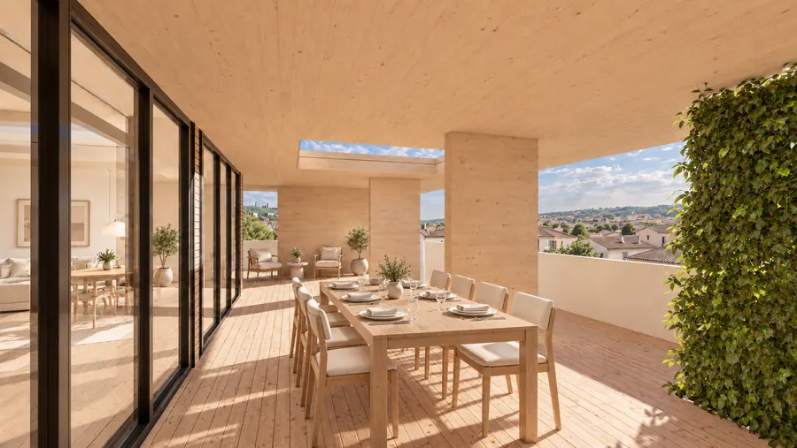 Eine lange Terrasse unter der Holzdecke: rechts eine berankte Wand, links die Fensterwand der Wohnung, in der Mitte ein gedeckter Tisch mit acht Stühlen; über dem Tisch eine Öffnung zum Himmel, dahinter der Blick über den Ort.