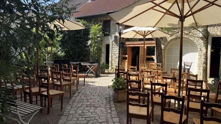 Blick über die Stuhlreihen im Hof auf die Arkaden des Alten Gutshofs, davor ein aufgespannter Sonnenschirm