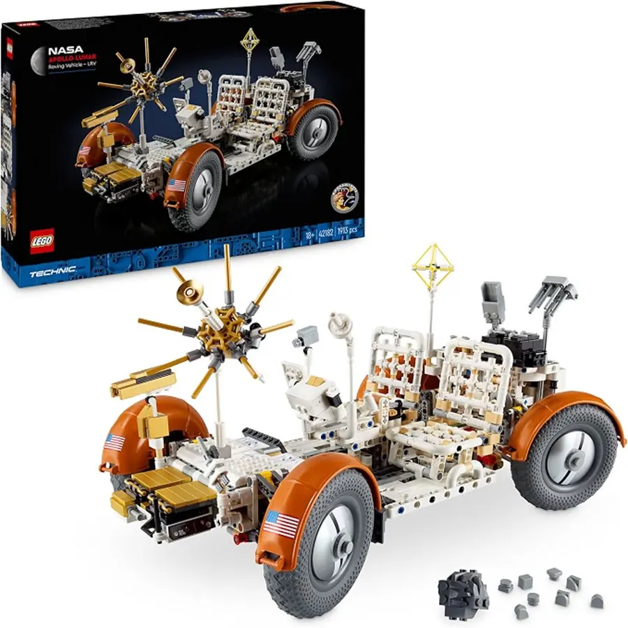 Ein zusammengebautes Modell des Apollo-Mondautos aus Klemmbausteinen: orangefarbene Kotflügel, Sitze aus weißen Teilen, Schirmantenne und Kamerastativ, dahinter der Karton des Bausatzes